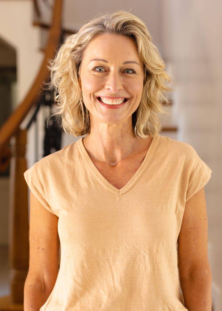portrait of caucasian senior woman smiling while standing in the living room at home. people and emotions concept, unaltered.